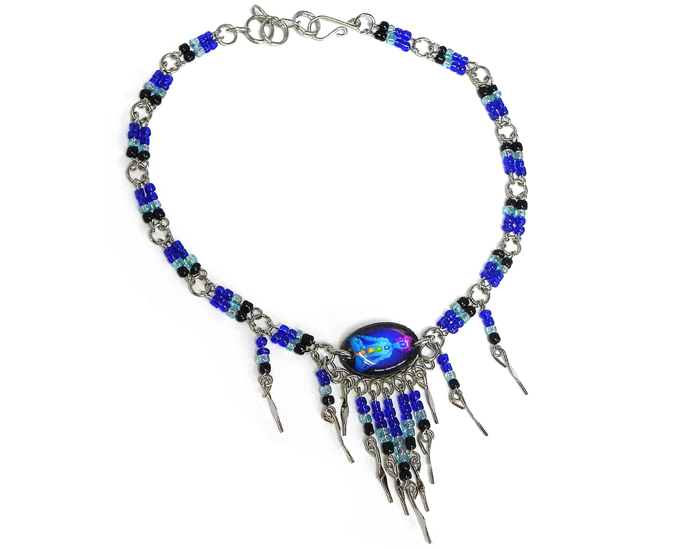Handmade seed bead alpaca silver metal chain anklet with oval-shaped acrylic New Age themed chakra graphic design and long beaded metal dangles in blue, light blue, black, and rainbow color combination.