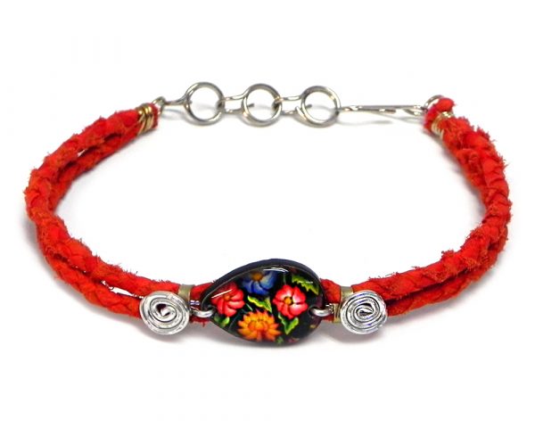 Handmade braided dyed leather bracelet with silver metal wire and teardrop-shaped acrylic vintage themed floral pattern graphic design centerpiece in red, black, and multicolored color combination.