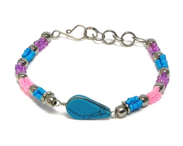 Handmade multicolored seed bead and silver metal bead rope-like bracelet with teardrop-cut turquoise howlite gemstone crystal cabochon centerpiece in turquoise blue, pink, and purple lavender color combination.