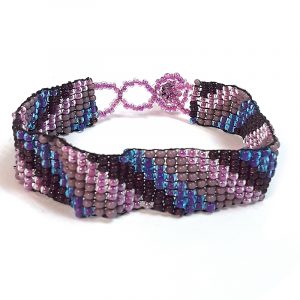 Handmade Czech glass seed bead thin strap bracelet with slanted striped pattern design in purple, burgundy, and pink color combination.