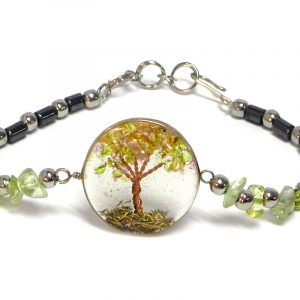 Handmade hematite, chip stone, and silver metal seed bead bracelet with round-shaped clear acrylic resin, copper wire, and crushed chip stone inlay tree of life centerpiece in lime green color.