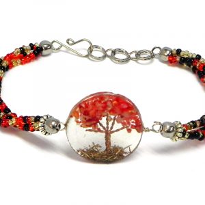 Handmade multicolored seed bead multi strand bracelet with round-shaped clear acrylic resin, copper wire, and crushed chip stone inlay tree of life centerpiece in red, gold, and black color combination.