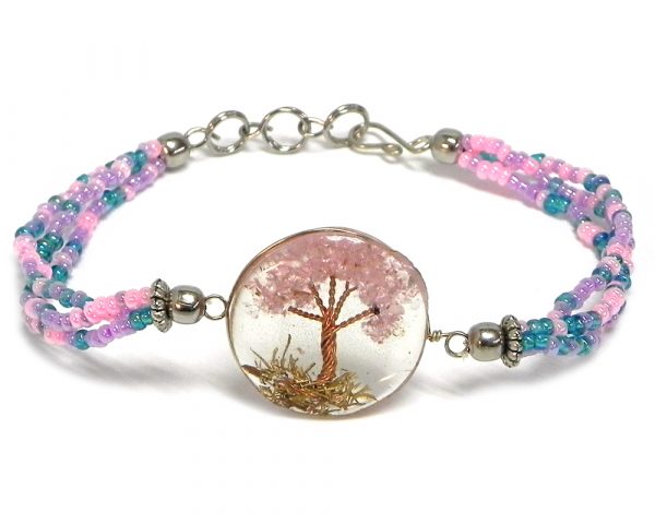 Handmade multicolored seed bead multi strand bracelet with round-shaped clear acrylic resin, copper wire, and crushed chip stone inlay tree of life centerpiece in pink, turquoise blue, and purple lavender color combination.