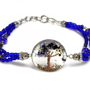 Handmade crystal bead and seed bead multi strand bracelet with round-shaped clear acrylic resin, copper wire, and crushed chip stone inlay tree of life centerpiece in blue, gold, and black color combination.