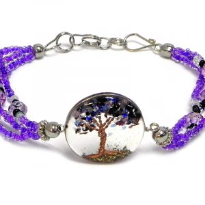 Handmade crystal bead and seed bead multi strand bracelet with round-shaped clear acrylic resin, copper wire, and crushed chip stone inlay tree of life centerpiece in purple, lavender, black, and clear color combination.