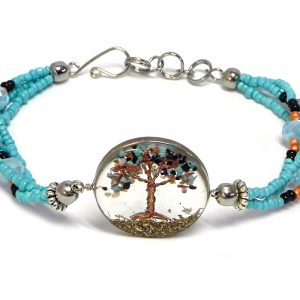 Handmade crystal bead and seed bead multi strand bracelet with round-shaped clear acrylic resin, copper wire, and crushed chip stone inlay tree of life centerpiece in light blue turquoise, orange, brown goldstone, and black color combination.