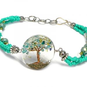Handmade crystal bead and seed bead multi strand bracelet with round-shaped clear acrylic resin, copper wire, and crushed chip stone inlay tree of life centerpiece in mint green, white, and gold color combination.