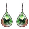 Teardrop-shaped thread dangle earrings with alpaca silver wire and monarch butterfly graphic image in green and orange color combination.