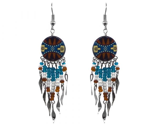 Handmade round-shaped ceramic earrings with handpainted tribal pattern design and long seed bead and alpaca silver metal dangles in brown, turquoise, white, black, and light yellow color combination.