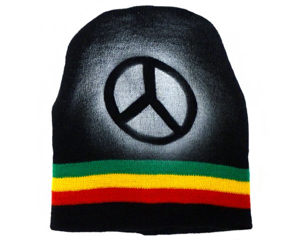 Handmade black knit beanie hat with horizontal stripes and spray painted peace sign design in Rasta colors.