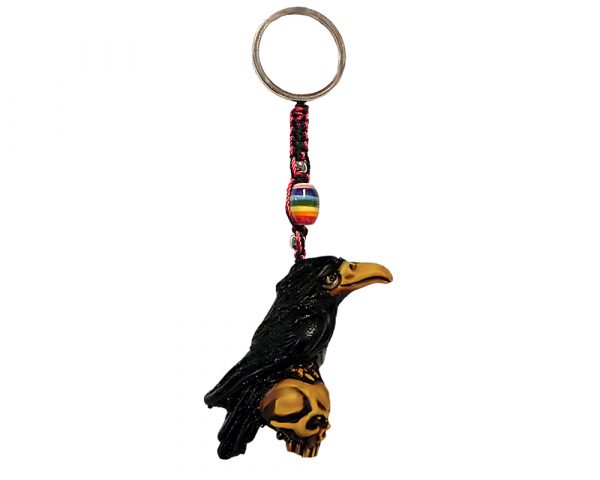 Handmade durepox resin figurine keychain of a black raven bird perched on a skull.