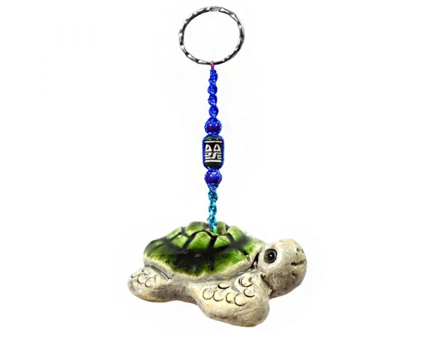 Handmade sea turtle animal keychain with handpainted ceramic, macramé string, a large bead, and metal keyring in green and beige color combination.