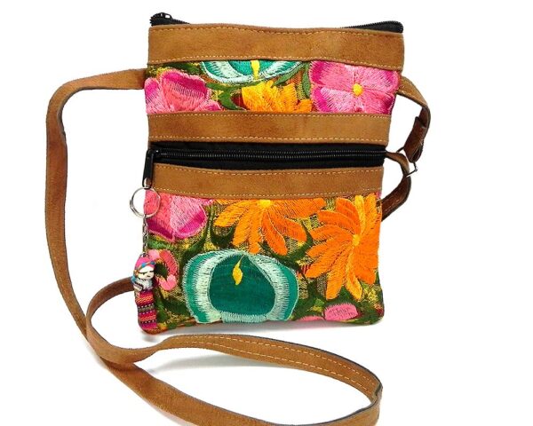 Medium-sized slim rectangle-shaped crossbody purse bag with multicolored embroidered floral designs, brown vegan leather suede, worry doll keychain, and yellow and lime green fabric.