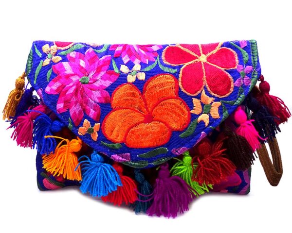 Handmade slim envelope purse bag with floral embroidered cotton material, pom pom fringe, magnetic snap closure, and a wristlet strap in blue and multicolored color combination.