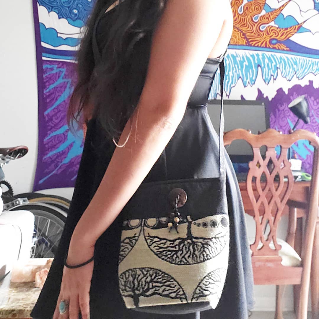 Medium-sized cushioned square-shaped purse bag with tree of life print pattern and coconut button and beads in beige and black color combination.
