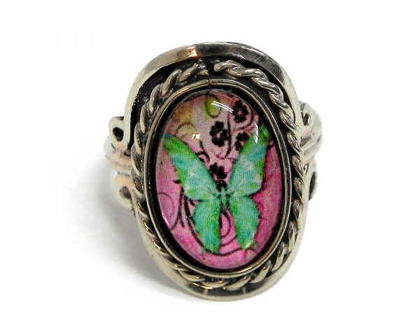 Handmade small oval-shaped acrylic vintage themed butterfly graphic design on alpaca silver metal ring with rope edge border in pink, mint, lime green, and black color combination.
