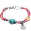 Handmade seed bead multi strand bracelet with silver metal seashell charm dangle, sea turtle shaped tumbled magnesite gemstone crystal, and clam shell bead centerpiece in salmon pink, turquoise, orange, white, and multicolored color combination.