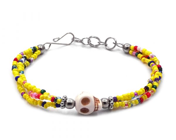 Handmade multicolored seed bead multi strand bracelet with skull shaped tumbled magnesite gemstone crystal centerpiece in yellow, white, beige, and multicolored color combination.