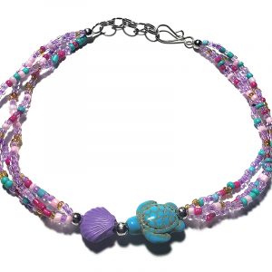 Handmade multicolored seed bead multi strand anklet with seashell bead and sea turtle shaped tumbled magnesite gemstone crystal centerpiece in lavender, purple, light pink, mint green, dark pink, and gold color combination.