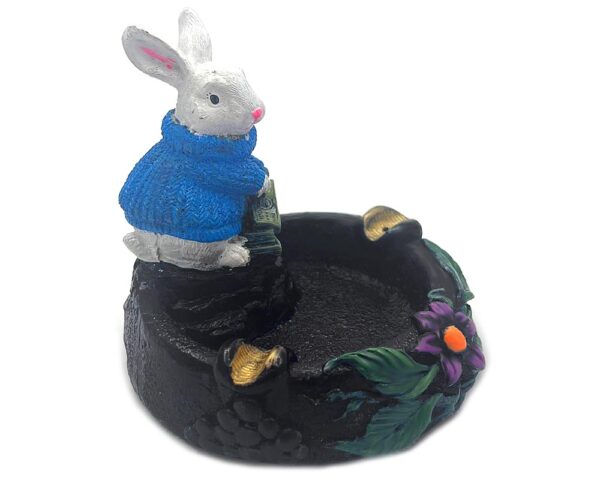 Handcrafted round incense holder ash tray with a flower and leaf design and 3D figurine of a rabbit holding money in turquoise, green, black, and gold color combination.